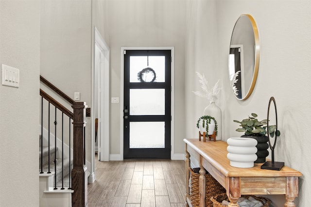 foyer with baseboards, wood finished floors, and stairs