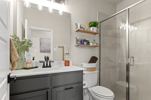 bathroom with toilet, a shower stall, and vanity