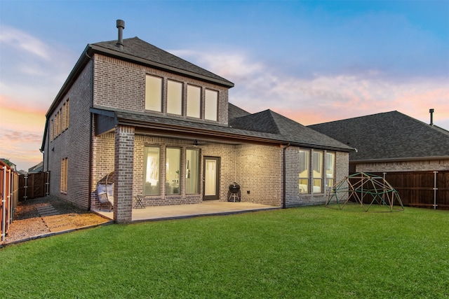 rear view of house featuring a yard, a fenced backyard, and brick siding