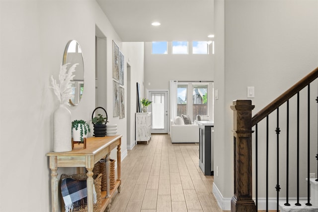 entryway with recessed lighting, stairway, baseboards, light wood-type flooring, and a high ceiling