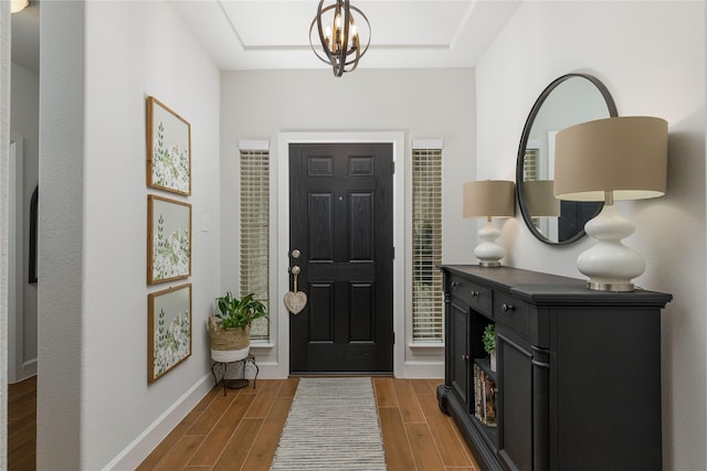 entrance foyer with a notable chandelier, light wood-type flooring, and baseboards