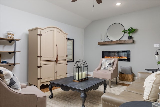 living area with light wood-type flooring, recessed lighting, vaulted ceiling, ceiling fan, and a glass covered fireplace