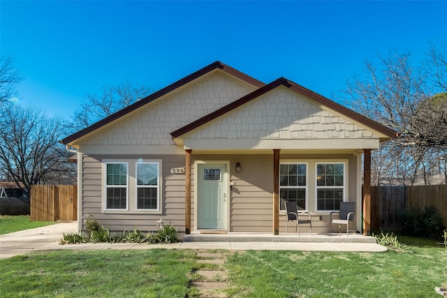 bungalow-style home with fence, a porch, and a front lawn