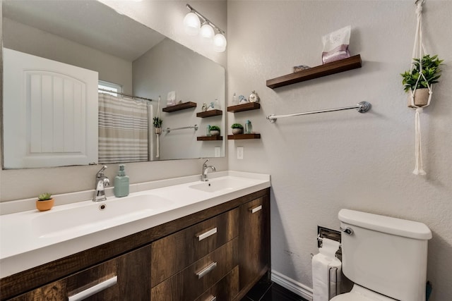 bathroom with toilet, double vanity, a sink, and baseboards