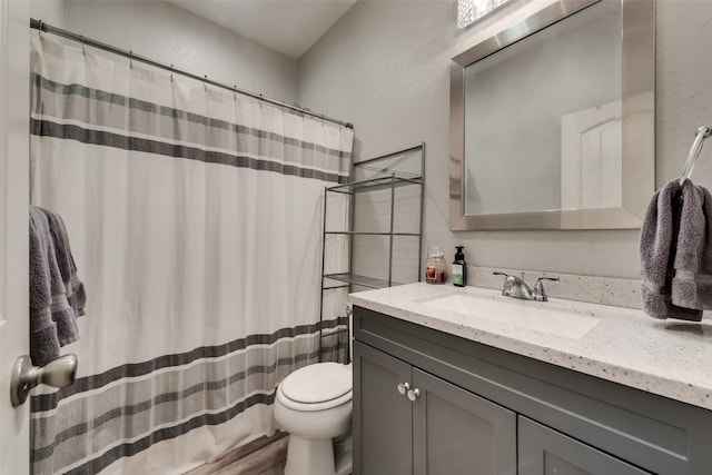 full bath with curtained shower, toilet, a textured wall, and vanity
