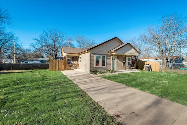 bungalow featuring concrete driveway, a front lawn, and fence