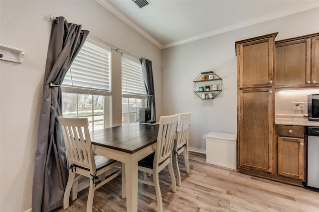 dining space featuring baseboards, visible vents, ornamental molding, and light wood-style flooring