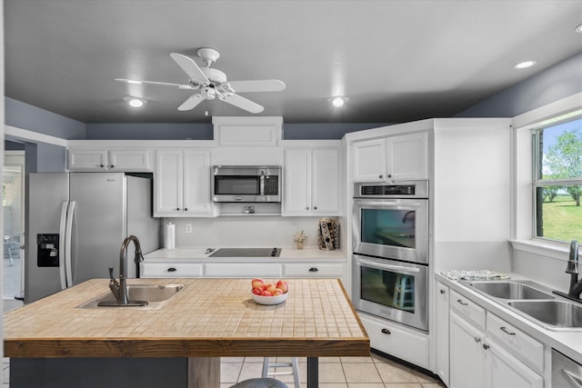 kitchen with appliances with stainless steel finishes, white cabinetry, and a sink