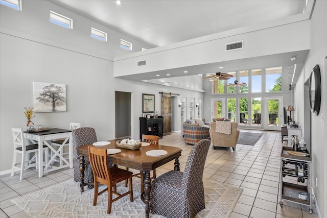 dining space with a barn door, light tile patterned floors, and a high ceiling