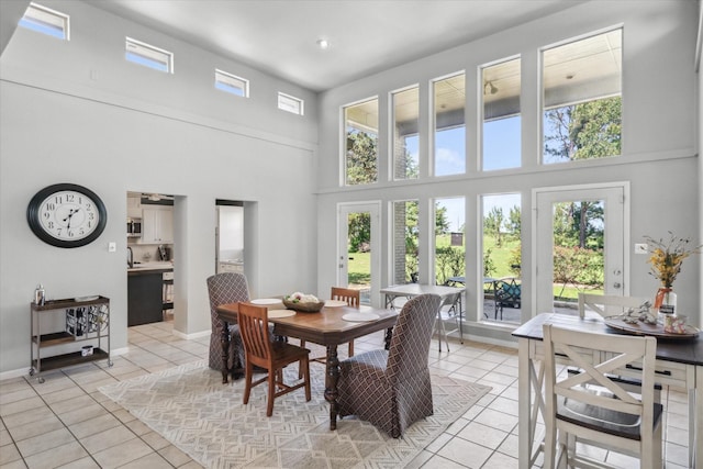 dining room with a high ceiling, light tile patterned flooring, and baseboards