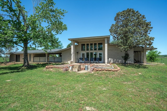 back of house featuring a patio, brick siding, fence, and a lawn