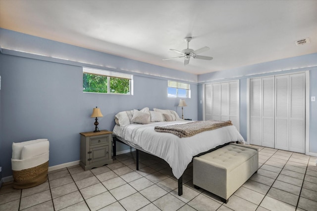 bedroom featuring light tile patterned floors, visible vents, ceiling fan, and baseboards