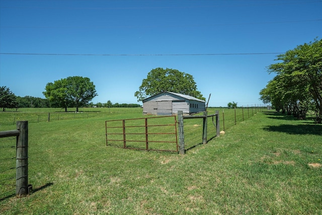 view of yard featuring fence, an outdoor structure, a rural view, and a detached garage