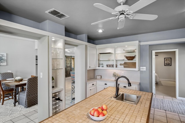 kitchen featuring open shelves, light countertops, white cabinets, a sink, and visible vents