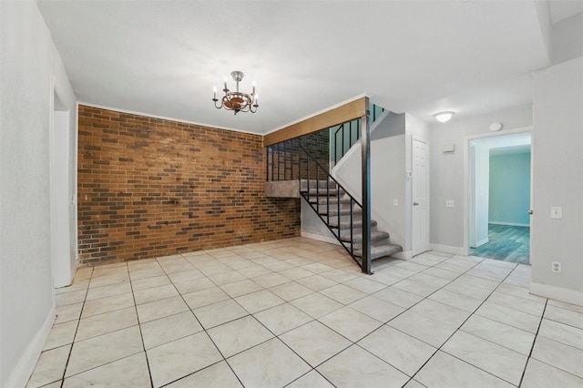 unfurnished room with an inviting chandelier, stairs, light tile patterned flooring, brick wall, and baseboards