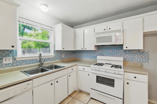 kitchen featuring decorative backsplash, a sink, light countertops, white cabinets, and white appliances