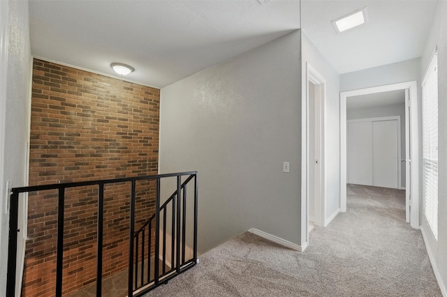 hallway with carpet floors, baseboards, an upstairs landing, and a wealth of natural light