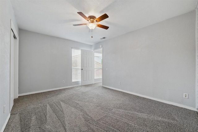 spare room featuring carpet floors, a ceiling fan, baseboards, and visible vents