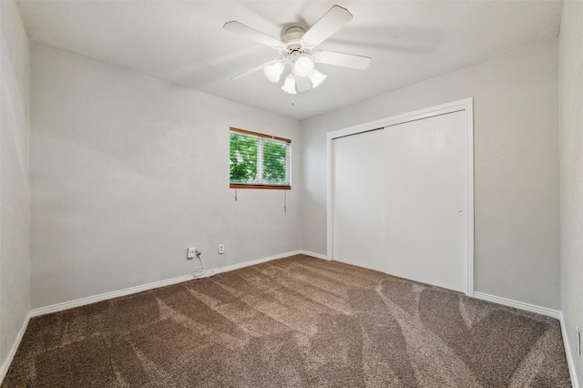 unfurnished bedroom with baseboards, ceiling fan, carpet, and a closet