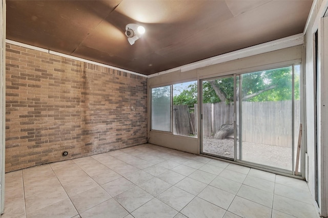 tiled empty room featuring brick wall