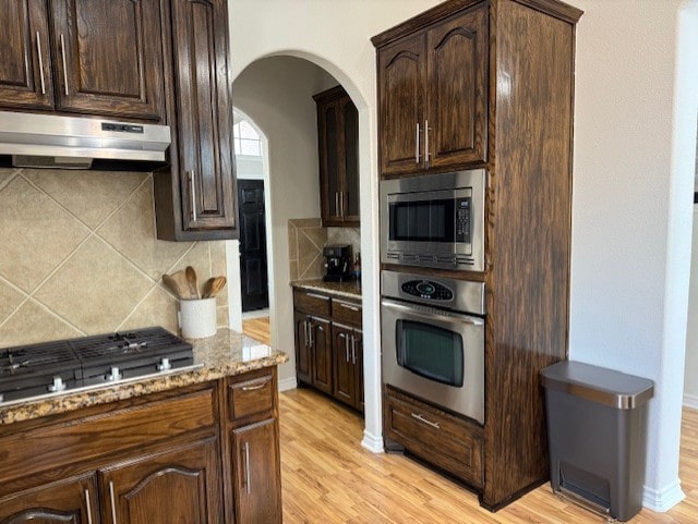 3609 S Texas Dr, Sachse, TX 75048 - kitchen featuring under cabinet range hood, appliances with stainless steel finishes, light stone counters, and tasteful backsplash