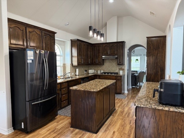 3609 S Texas Dr, Sachse, TX 75048 - kitchen with dark brown cabinetry, arched walkways, a center island, freestanding refrigerator, and under cabinet range hood
