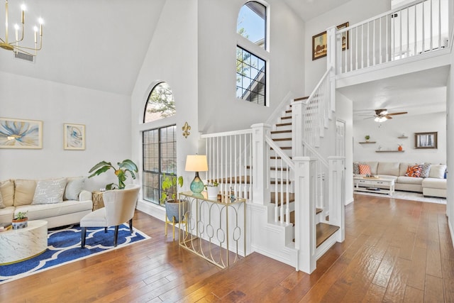 living area with wood-type flooring, a wealth of natural light, stairs, and a high ceiling