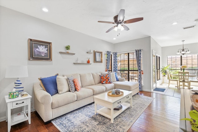 living room with hardwood / wood-style flooring, visible vents, baseboards, recessed lighting, and ceiling fan with notable chandelier