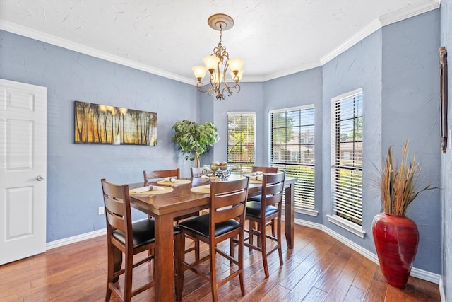 dining space featuring wood-type flooring, an inviting chandelier, ornamental molding, and baseboards