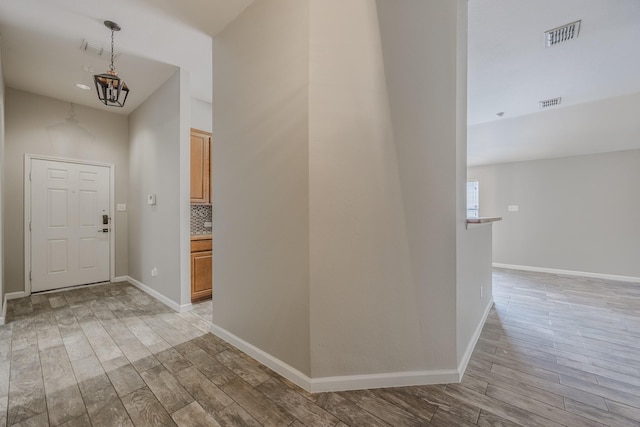 foyer with light wood-style floors, visible vents, and baseboards