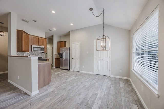 kitchen with appliances with stainless steel finishes, visible vents, a notable chandelier, and brown cabinetry