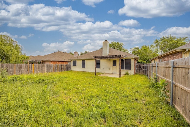 rear view of property with a chimney, a yard, a patio area, and a fenced backyard