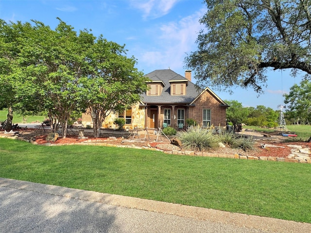 craftsman house featuring a chimney, brick siding, a shingled roof, and a front lawn