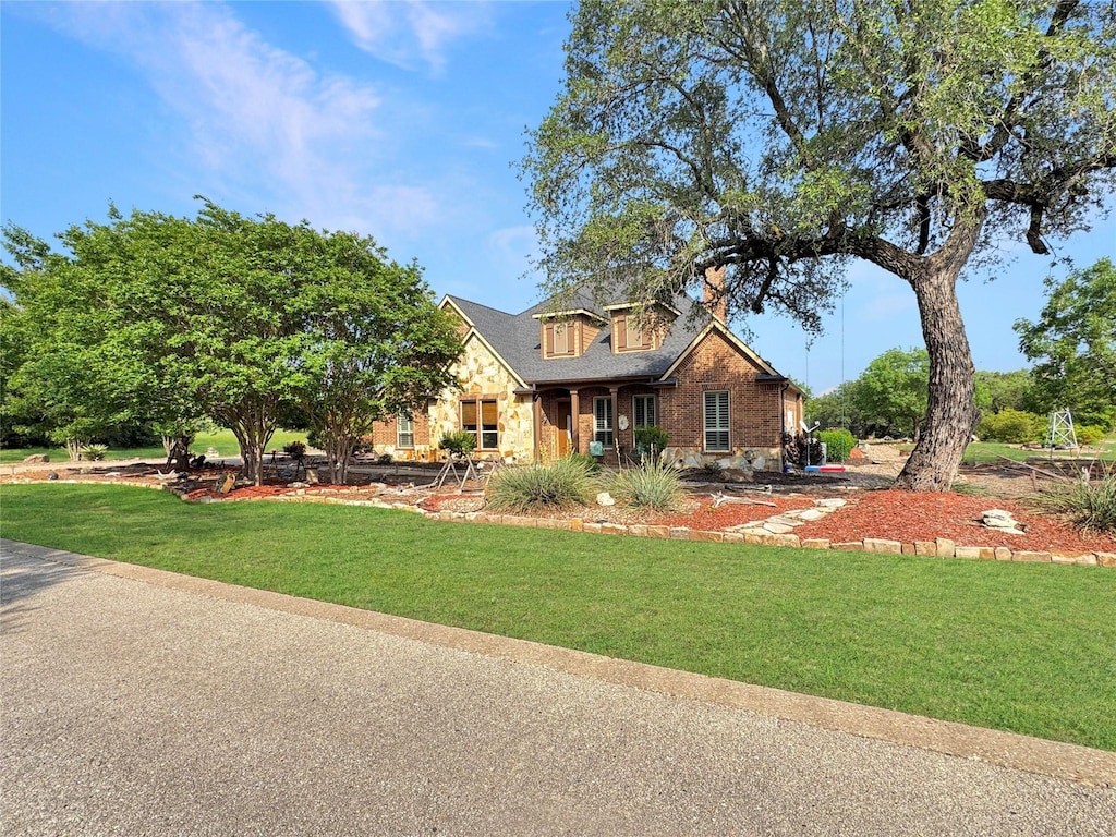 view of front of home featuring brick siding, a front yard, and stone siding