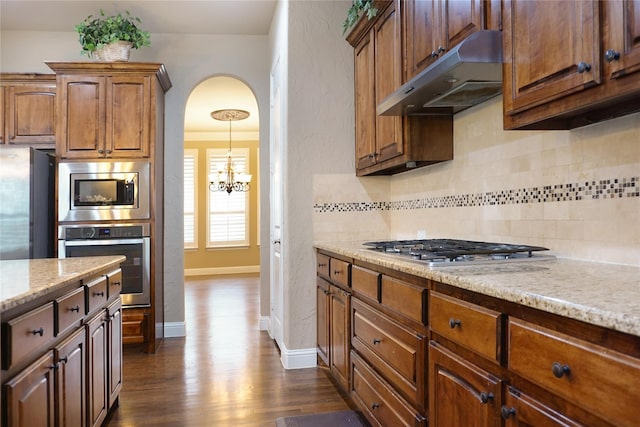 1852 Audubon Pond Way, Allen, TX 75013 - kitchen featuring under cabinet range hood, dark wood finished floors, backsplash, a notable chandelier, and stainless steel appliances