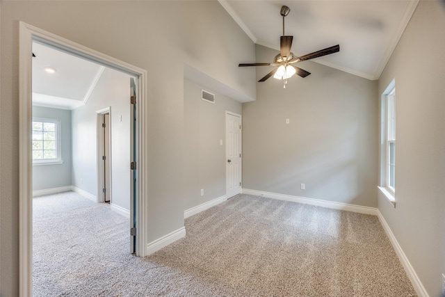 spare room featuring ceiling fan, visible vents, light carpet, ornamental molding, and lofted ceiling