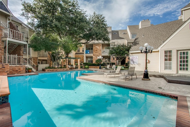 community pool with a residential view and a patio area