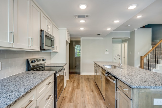 kitchen featuring stainless steel appliances, light wood-style floors, a sink, baseboards, and visible vents