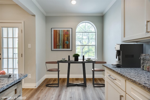dining room with crown molding, light wood finished floors, and baseboards