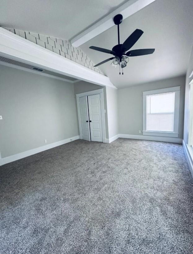 interior space featuring baseboards, visible vents, lofted ceiling with beams, and a ceiling fan
