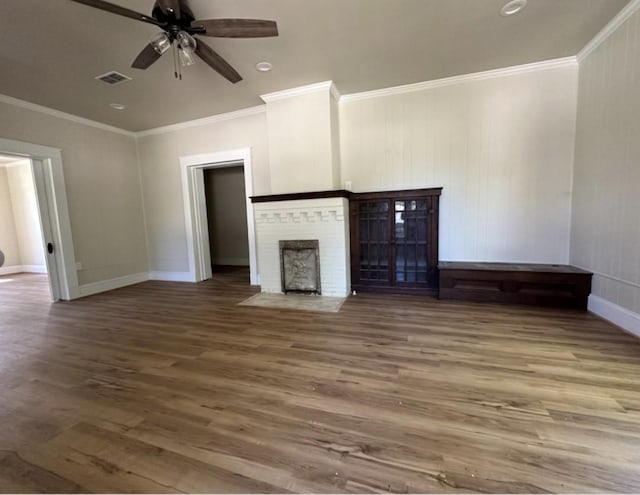 unfurnished living room with wood finished floors, ceiling fan, a fireplace, baseboards, and crown molding