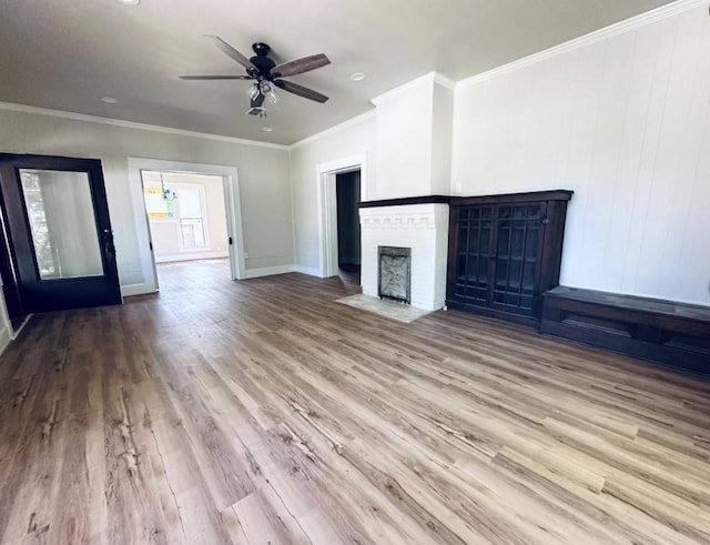 unfurnished living room featuring a brick fireplace, a ceiling fan, baseboards, ornamental molding, and wood finished floors