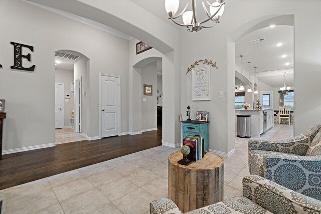 living room featuring light tile patterned floors, visible vents, a notable chandelier, and arched walkways
