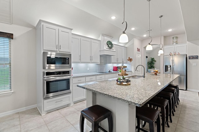 kitchen with tasteful backsplash, appliances with stainless steel finishes, a kitchen bar, a sink, and visible vents