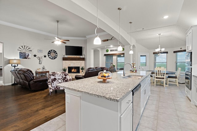 kitchen featuring a warm lit fireplace, open floor plan, appliances with stainless steel finishes, and a sink