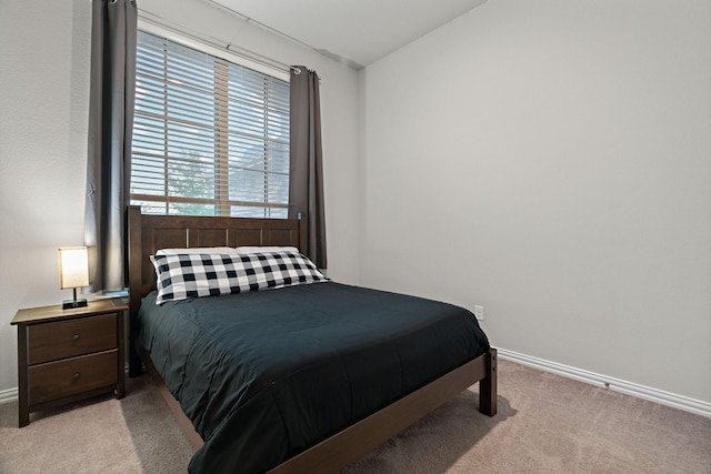 bedroom featuring lofted ceiling, light colored carpet, and baseboards