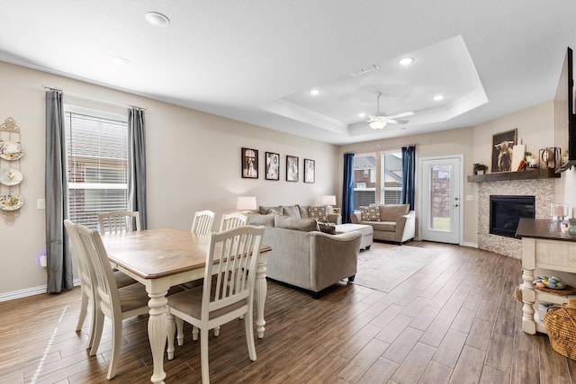 dining area with wood finished floors, ceiling fan, and a tray ceiling