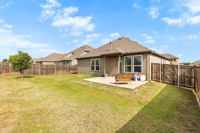 rear view of house featuring a patio area, a yard, a shingled roof, and a fenced backyard