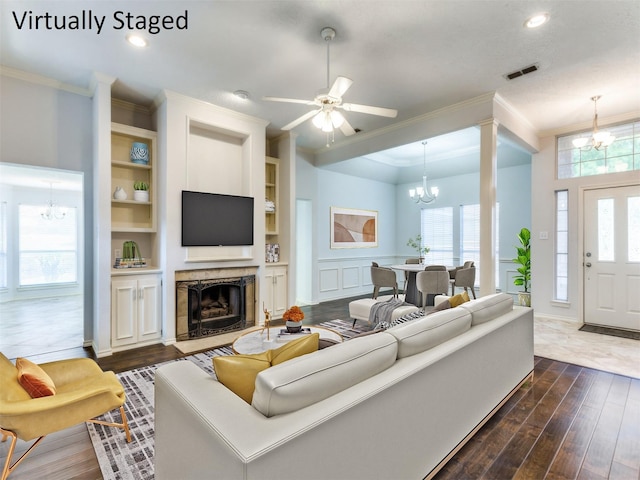 living area with ornamental molding, dark wood-style floors, a premium fireplace, and visible vents