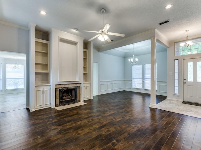 unfurnished living room with a tile fireplace, a decorative wall, ornamental molding, and dark wood finished floors